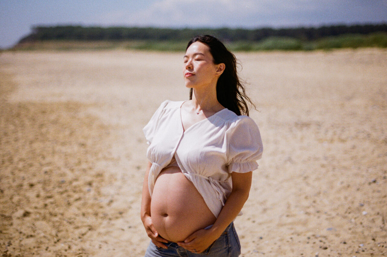 Maternity photo of a mother on a beach.