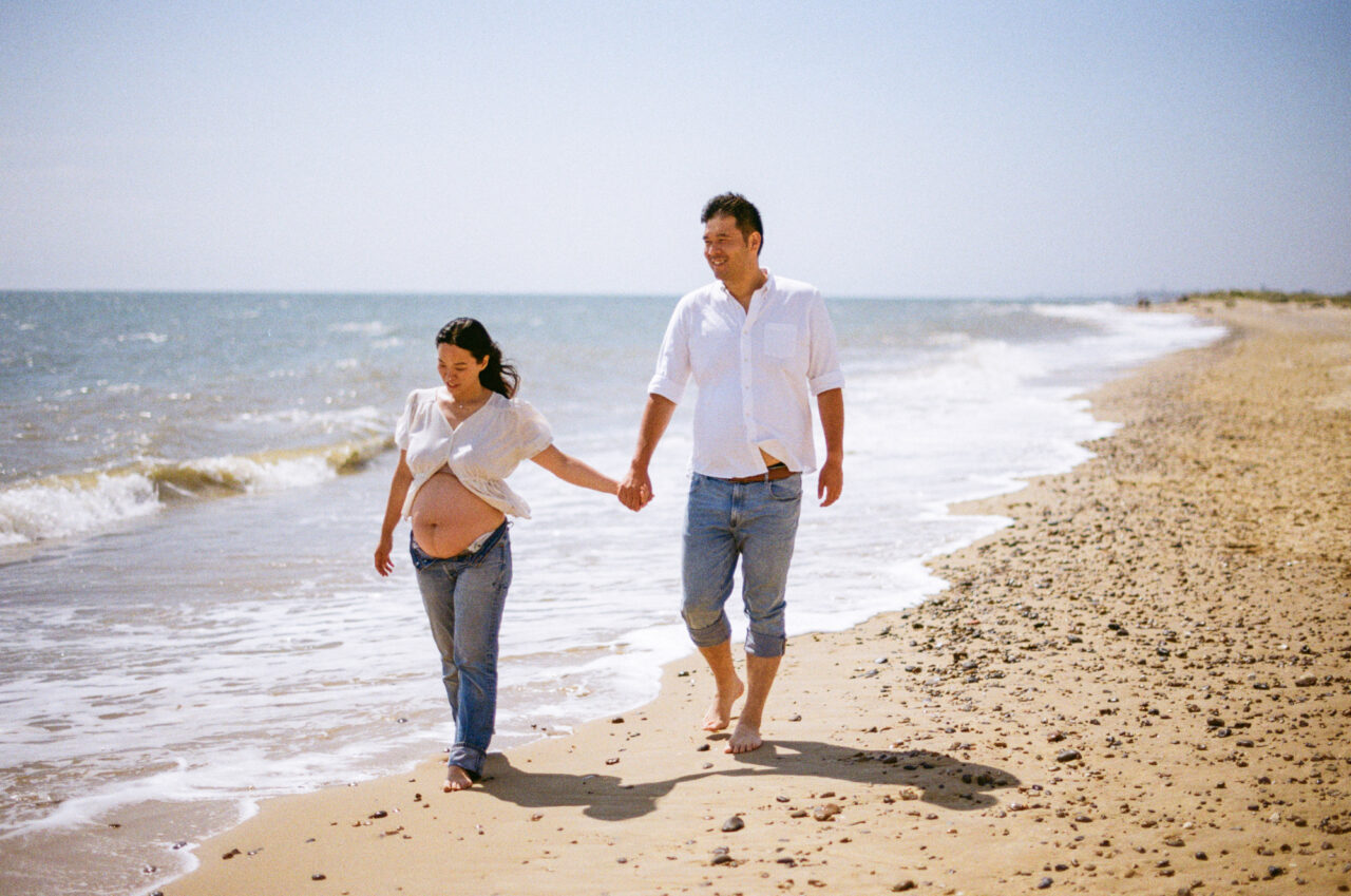 Maternity photo of a mother and father on a beach.