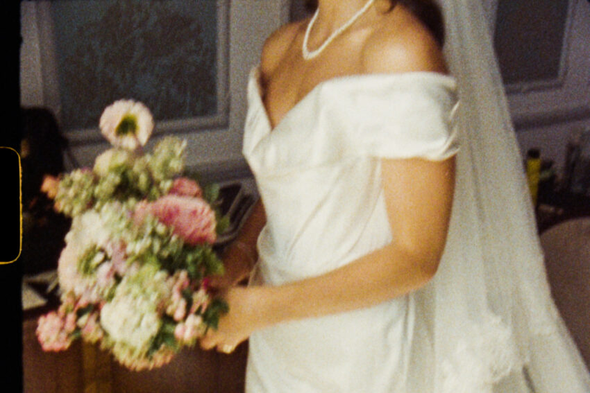 Still from a Super 8 wedding film showing a bride and her flowers.
