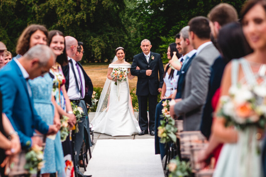 Bride walking down the aisle with her father during a Lincolnshire wedding, photographed in an elegant, documentary style.
