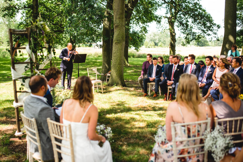 Outdoor wedding ceremony photographed by a Lincolnshire wedding photographer, capturing guests gathered beneath trees during a relaxed countryside celebration.