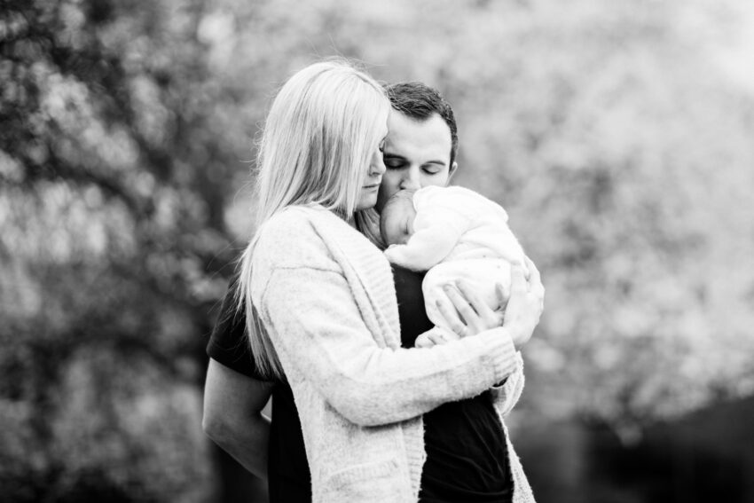 Portrait of mother, father and newborn child in a London park.