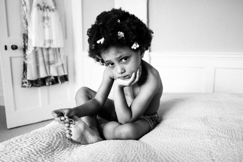 Portrait of a flowergirl sitting on a bed