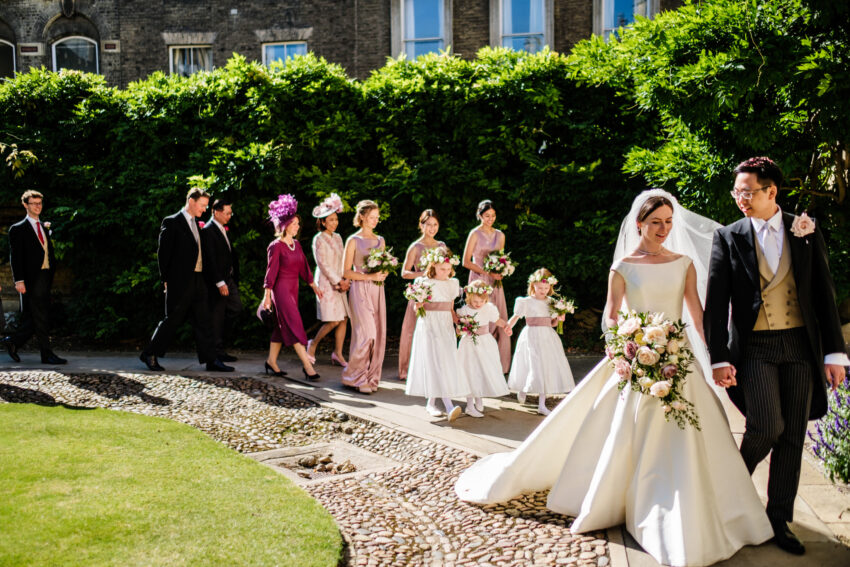 Bride and groom walking back from the ceremony at Sidney Sussex College, surrounded by wedding guests