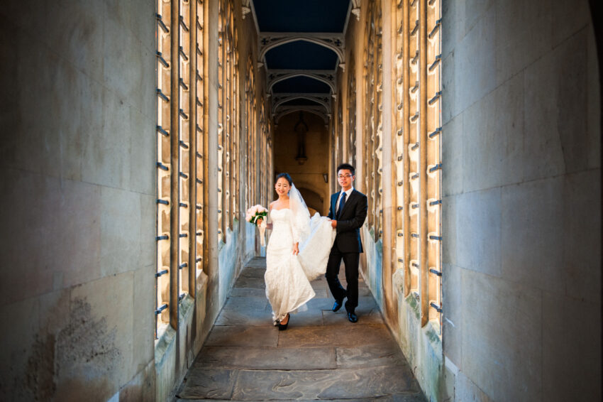 Bride and groom walking together across the Bridge of Sighs in Cambridge