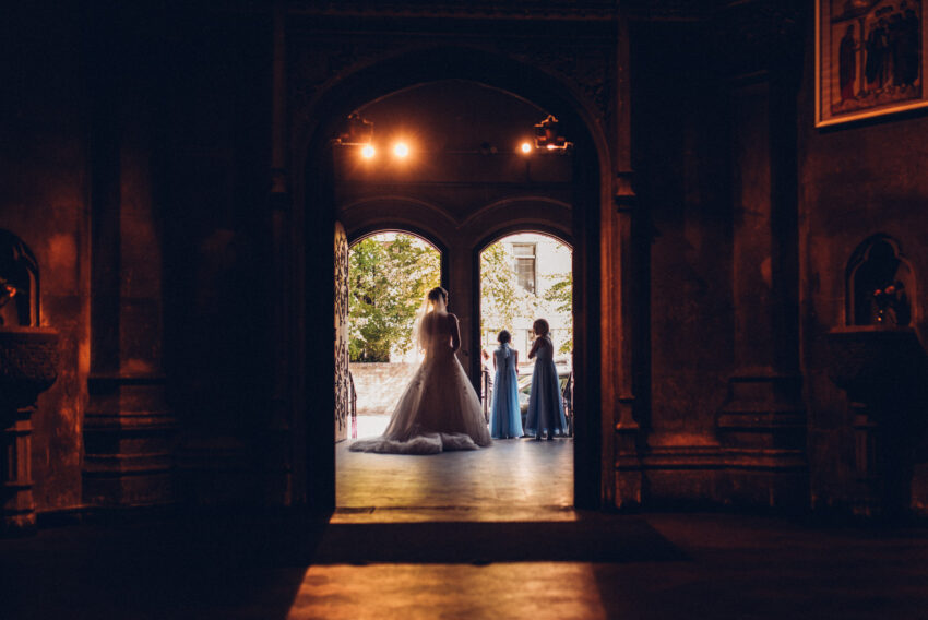Bride framed in silhouette beneath the arches at Our Lady and the English Martyrs Church