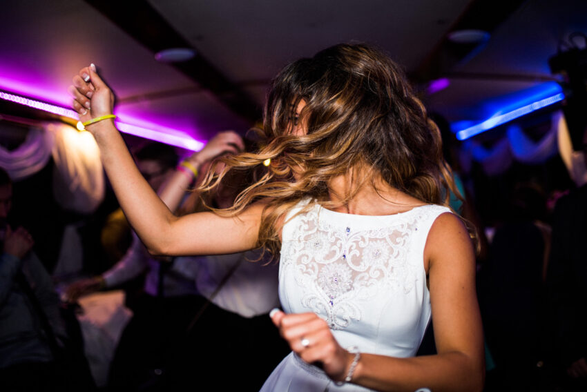 Bride dancing on a party boat during an evening celebration on the River Cam