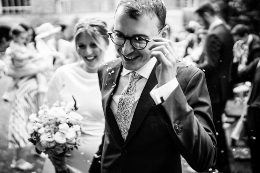 Bride and groom walking through confetti at Sidney Sussex College, Cambridge