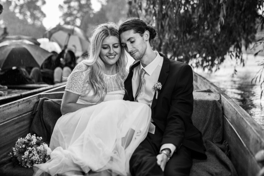 Bride and groom punting together in the rain on the River Cam