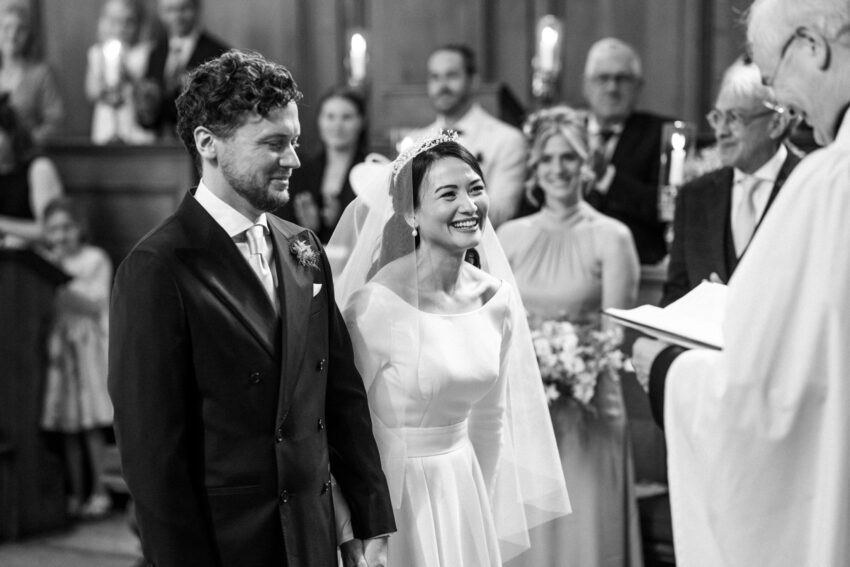 Bride and groom smiling during the ceremony, photographed inside a Cambridge college chapel