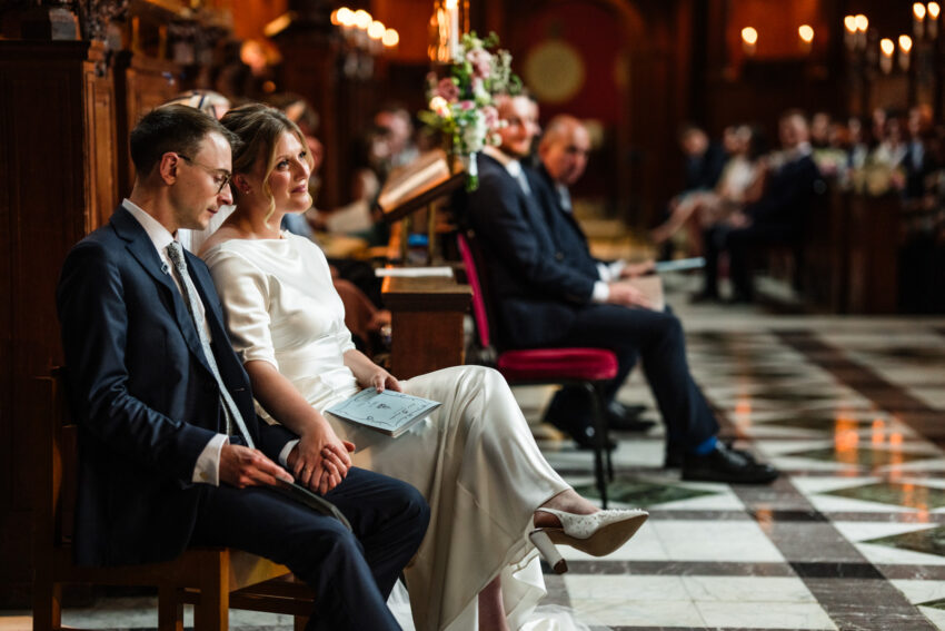 Bride and groom seated together during the ceremony at Sidney Sussex College