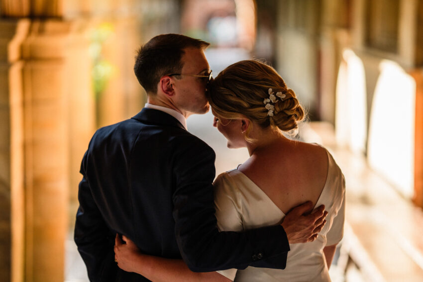 Bride and groom sharing a quiet embrace in the cloisters at Sidney Sussex College, Cambridge