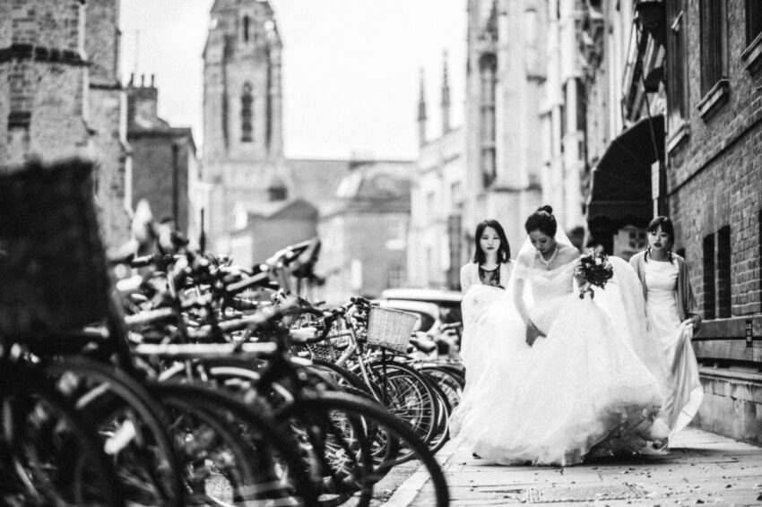 Bride and bridesmaids walking along King’s Parade in Cambridge, black and white wedding photograph