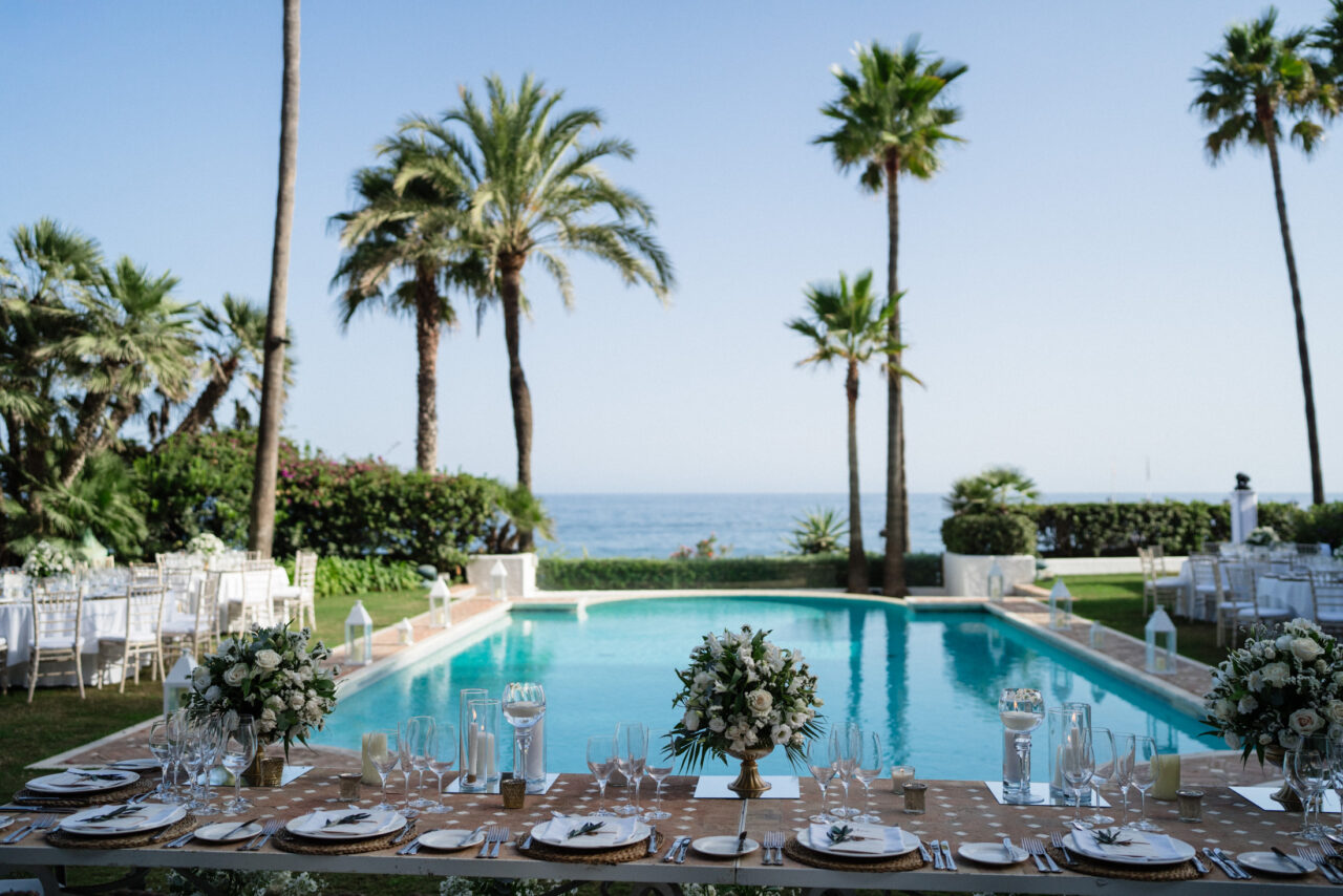 Poolside wedding reception setup with palm trees and sea views on the Costa del Sol
