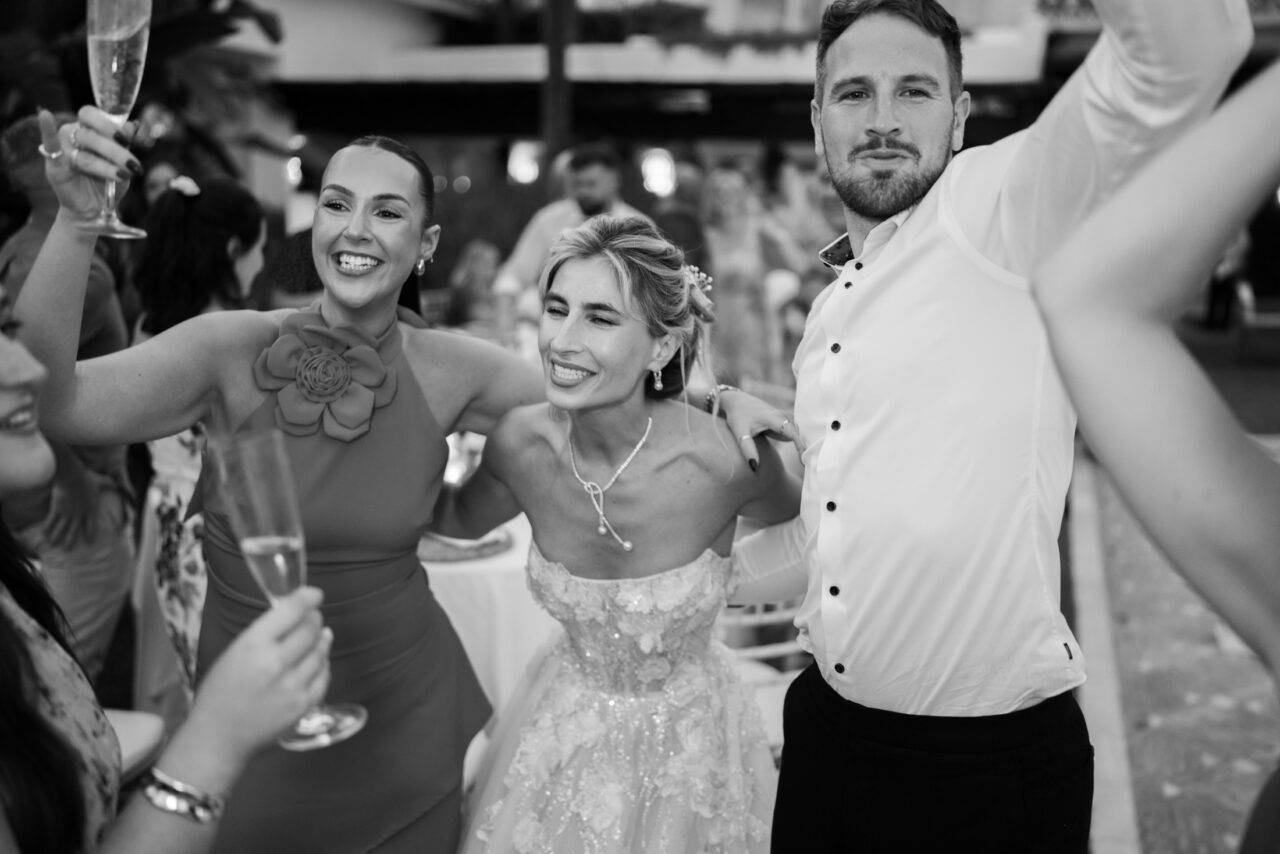 Black-and-white photo of guests cheering and celebrating during the wedding party