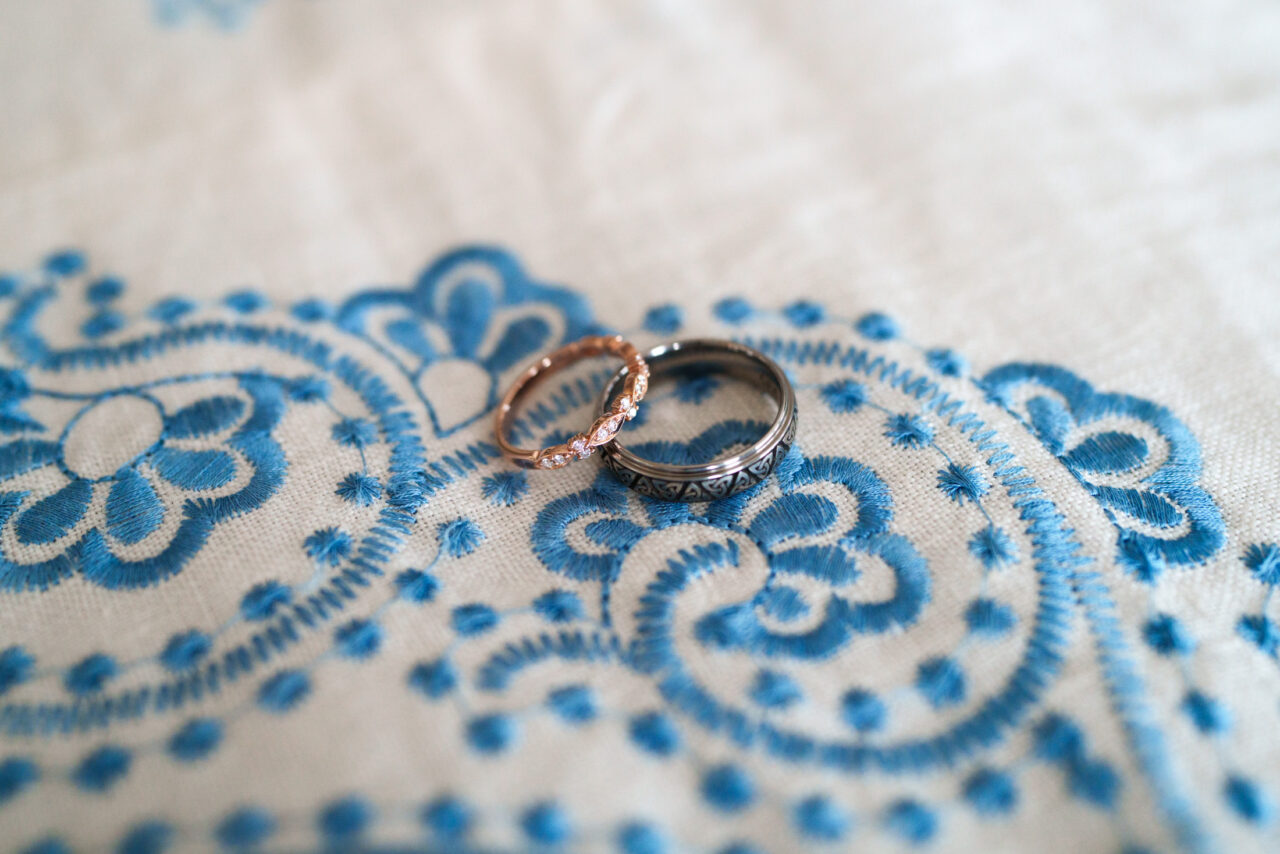 Wedding rings on embroidered fabric with blue detail, elegant Marbella wedding photography