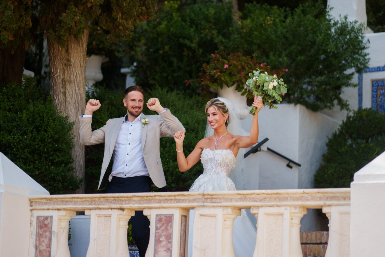 Bride and groom celebrate on a balcony.