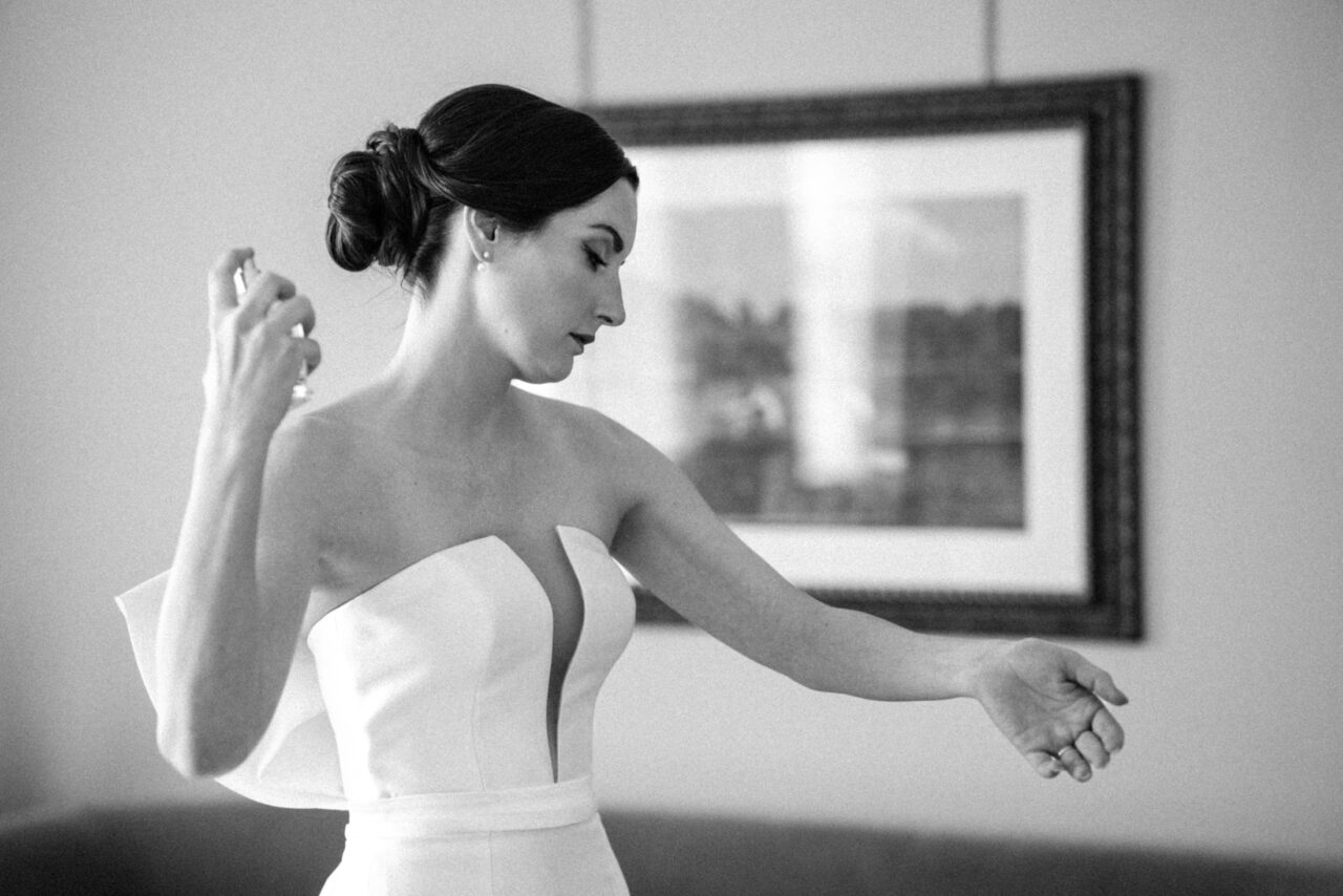 Black-and-white photo of the bride spraying perfume before the ceremony, bridal preparations