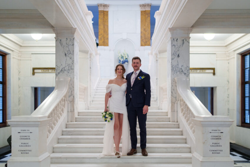 Bride and groom posing together on the marble staircase inside Camden Town Hall.