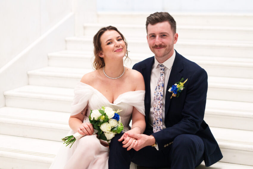 Bride and groom smiling together during a relaxed portrait on the stairs.