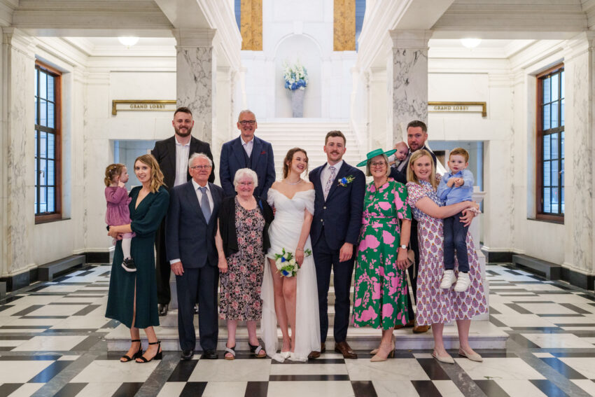Group photo of family and friends gathered with the bride and groom inside Camden Town Hall.