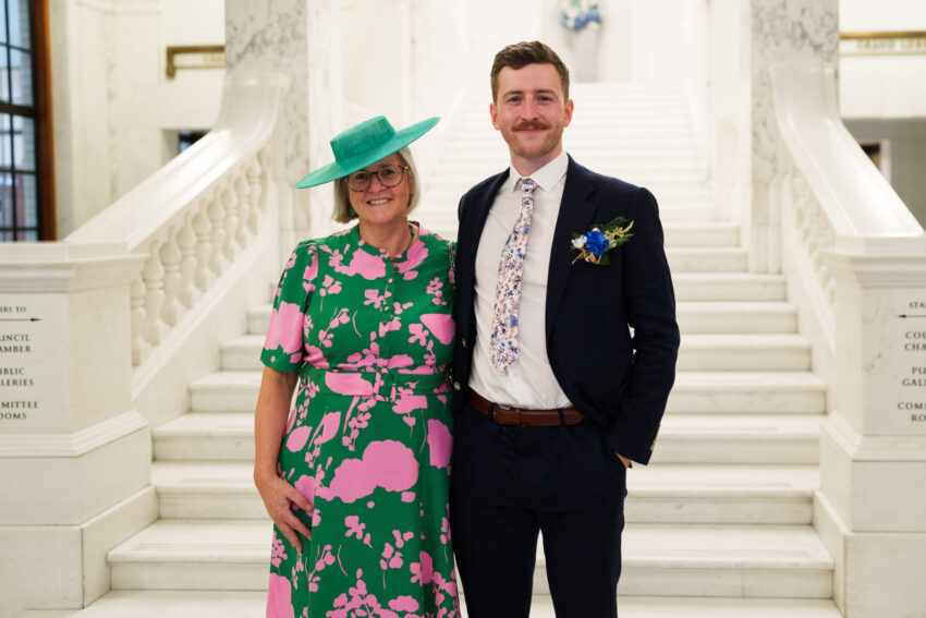 Groom standing with a guest on the marble staircase after the ceremony.