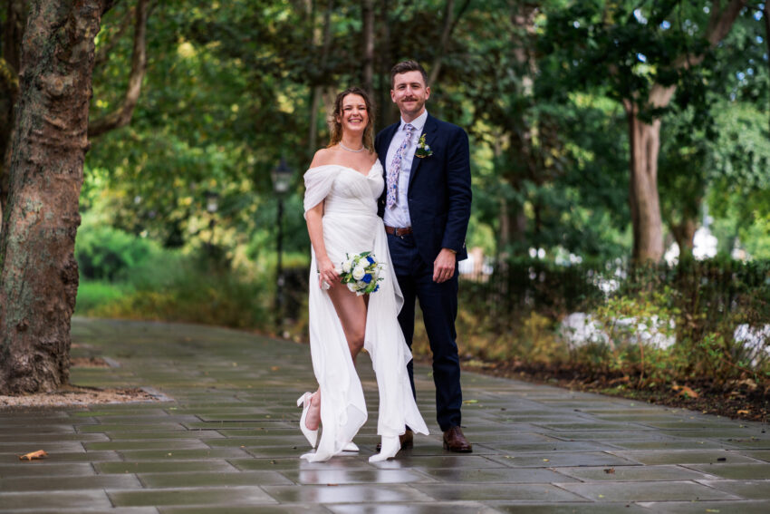 Bride and groom walking together along a tree-lined path after their wedding.