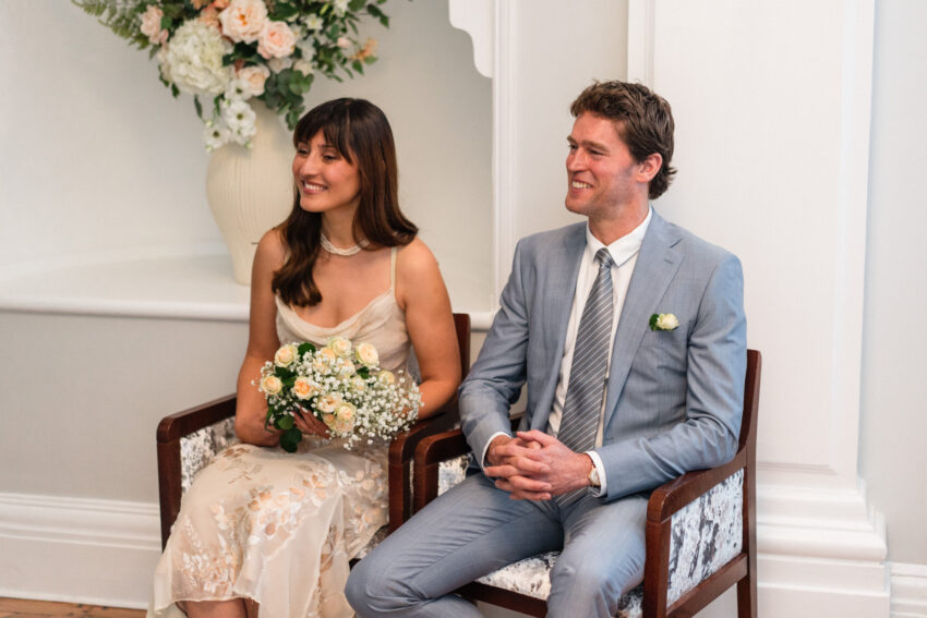 Bride and groom seated together during their Chelsea Old Town Hall wedding ceremony.