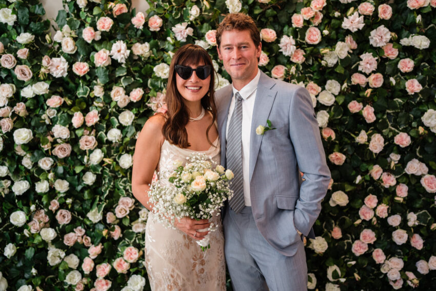 Bride and groom portrait by the flower wall at Chelsea Old Town Hall.