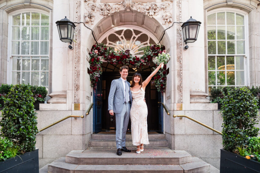 Bride and groom standing on the steps outside Chelsea Old Town Hall.