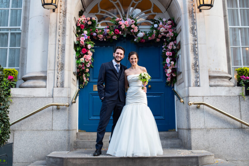 Bride and groom portrait outside Chelsea Old Town Hall under the floral entrance.