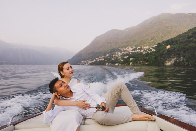 Couple lying together on a boat with Lake Como in the background.