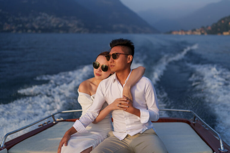 Couple holding hands while seated on a boat during a Lake Como couples photoshoot.