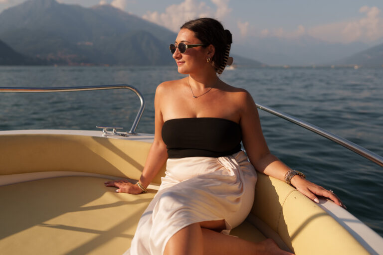 Woman sitting relaxed on a boat, enjoying the lake during a Lake Como couples photoshoot.