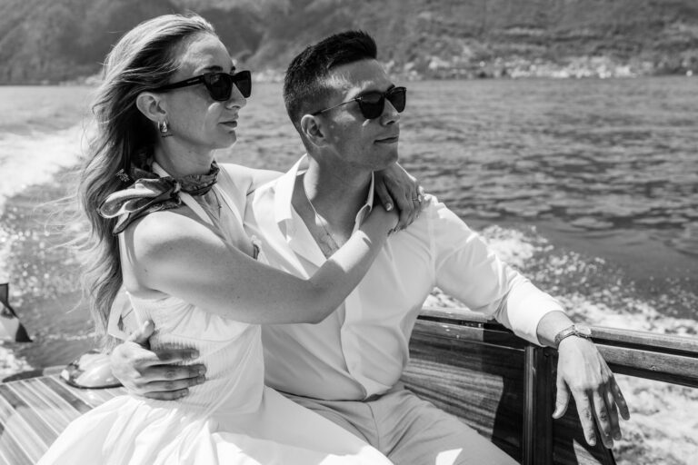 Black and white portrait of a couple sitting close together on a boat during a Lake Como couples photoshoot.