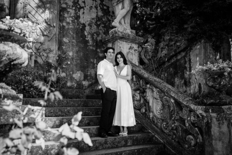 Couple standing close together and holding hands beneath the colonnade at Villa Monastero during a Lake Como couples photoshoot.