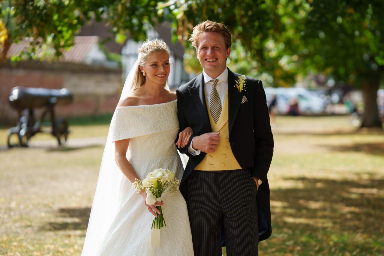 Bride and groom walking together outdoors after the ceremony, dappled sunlight filtering through trees and a relaxed, informal composition.