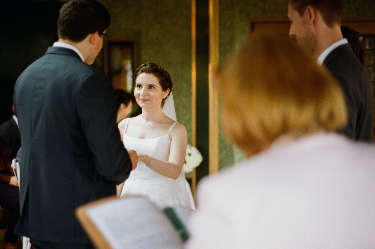 Wide view of the ceremony space with guests standing, floral arrangements and architectural symmetry shaping the final composition.