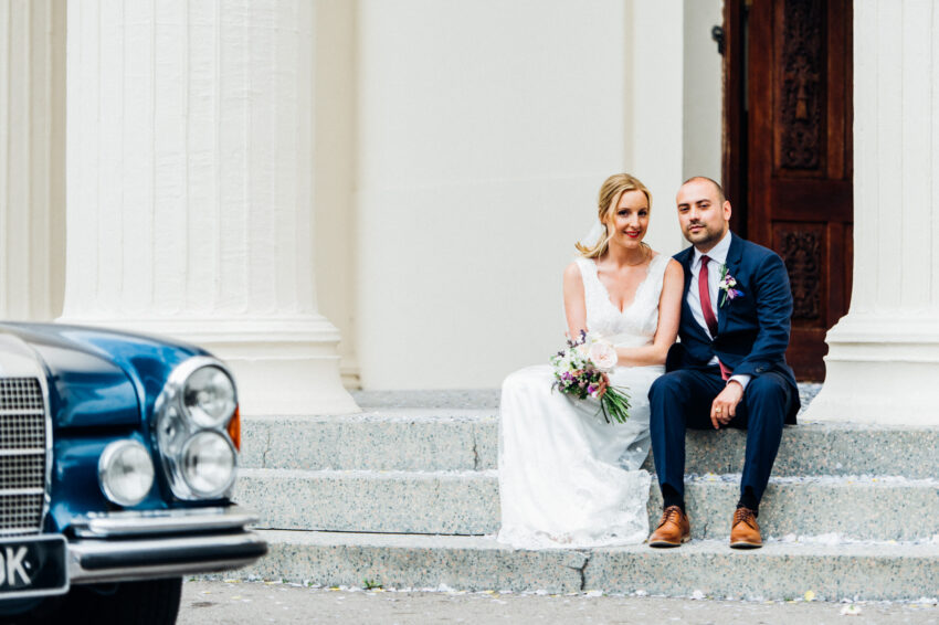 Bride and groom seated on steps, calm moment before the ceremony.