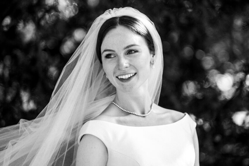 Bride smiling in black and white, relaxed and elegant portrait.