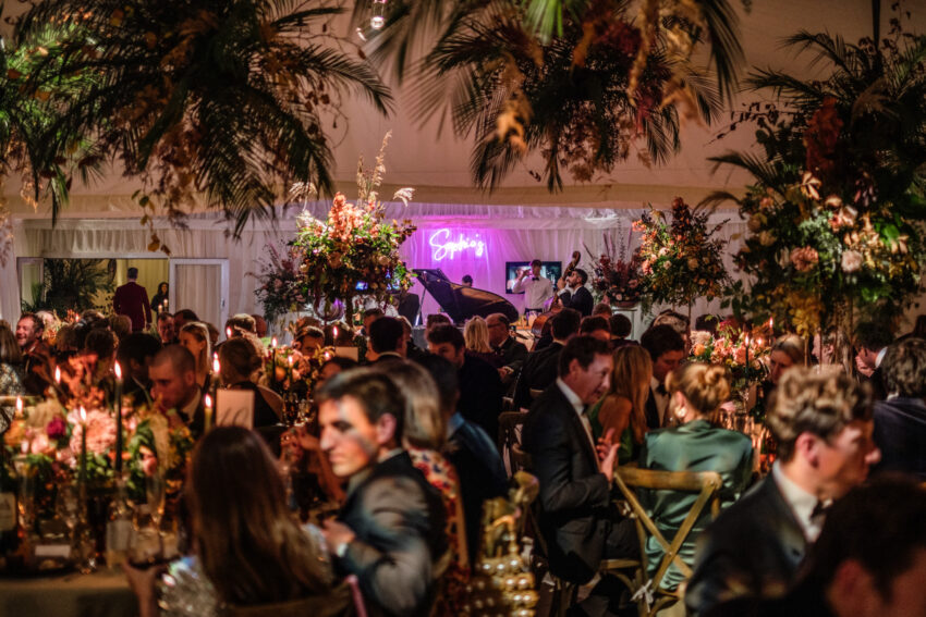 Evening wedding reception with guests mingling, warm lights and energy.