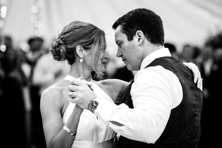 Bride and groom dancing together, intimate moment in black and white.