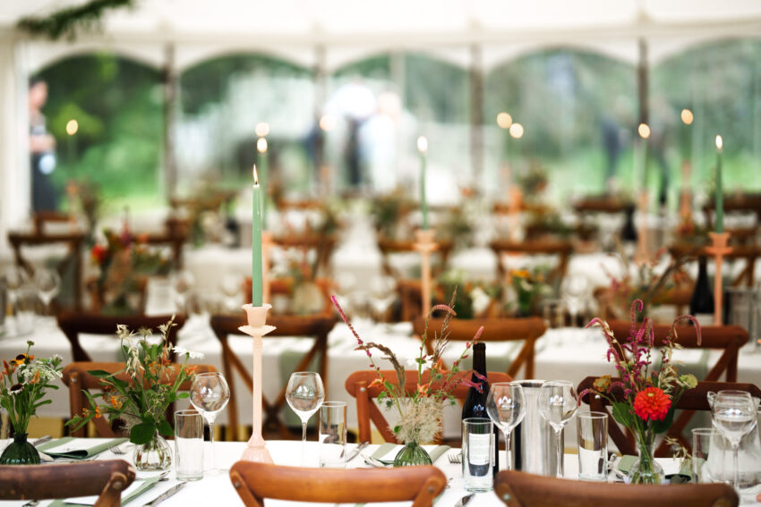 Wedding table setting under a marquee, soft light and rustic details.