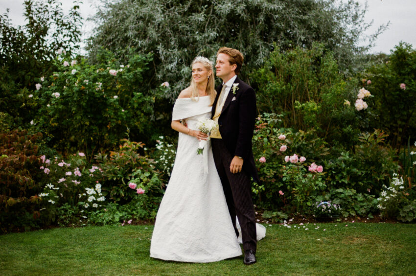 Bride and groom standing together in a garden during an Essex wedding portrait.