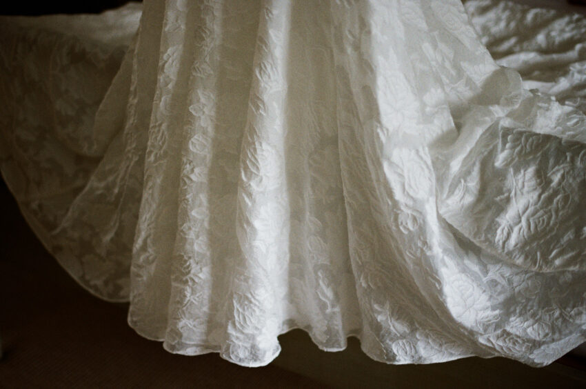 Close detail of a wedding dress hem, textured fabric and gentle folds.