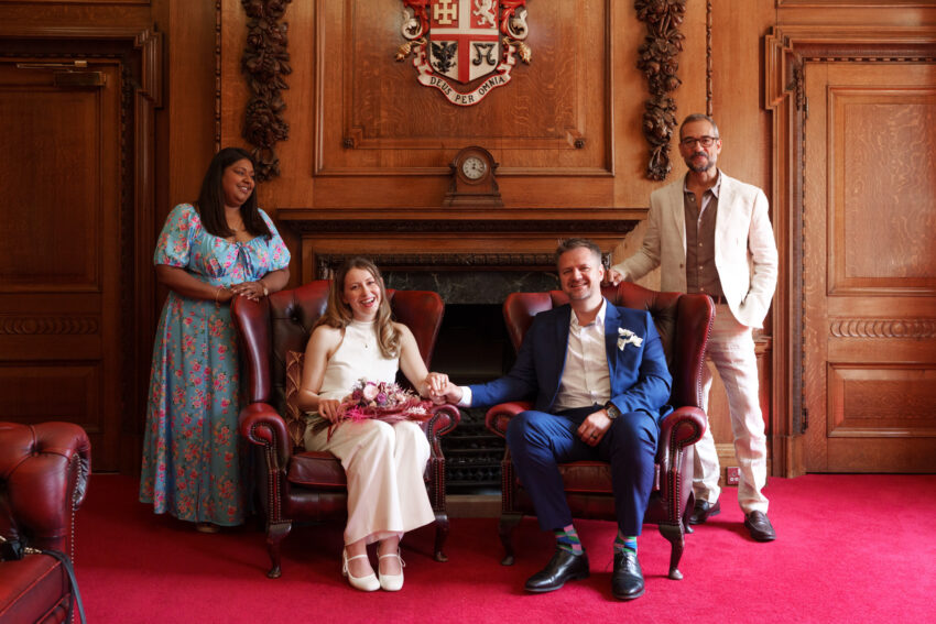 Group portrait of the newly married couple with friends inside the Mayor’s Parlour.