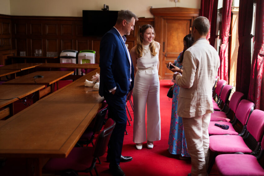 Bride and groom talking with guests inside the ceremony room at Islington Town Hall before the wedding.