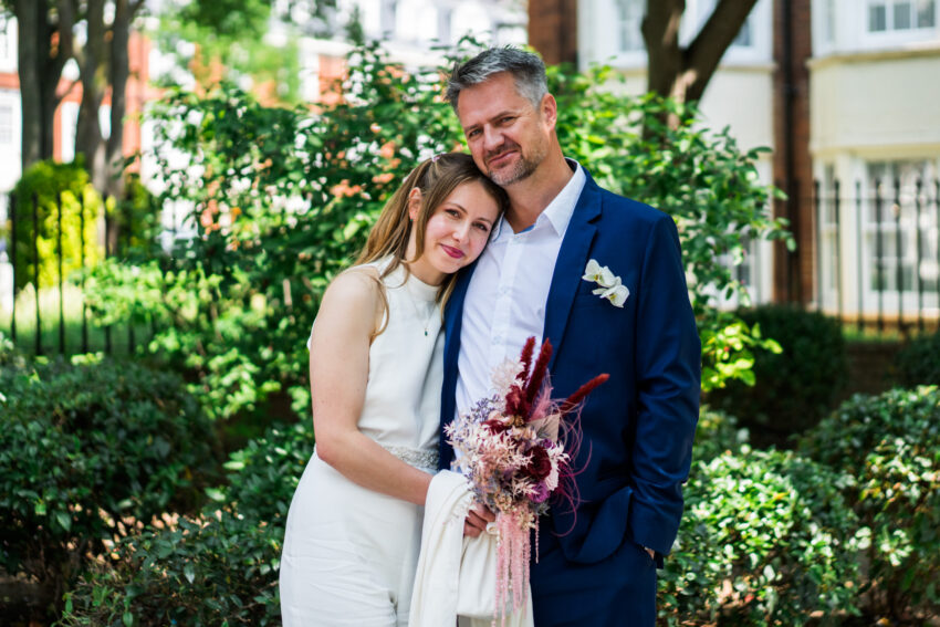 Relaxed outdoor portrait of the bride and groom holding flowers after their Islington Town Hall wedding.
