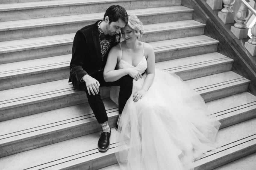Bride and groom sitting together on the steps at Islington Town Hall in a quiet moment.