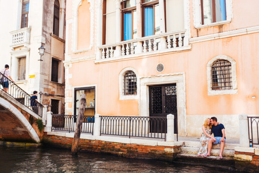 Couple sitting beside a canal in Venice.